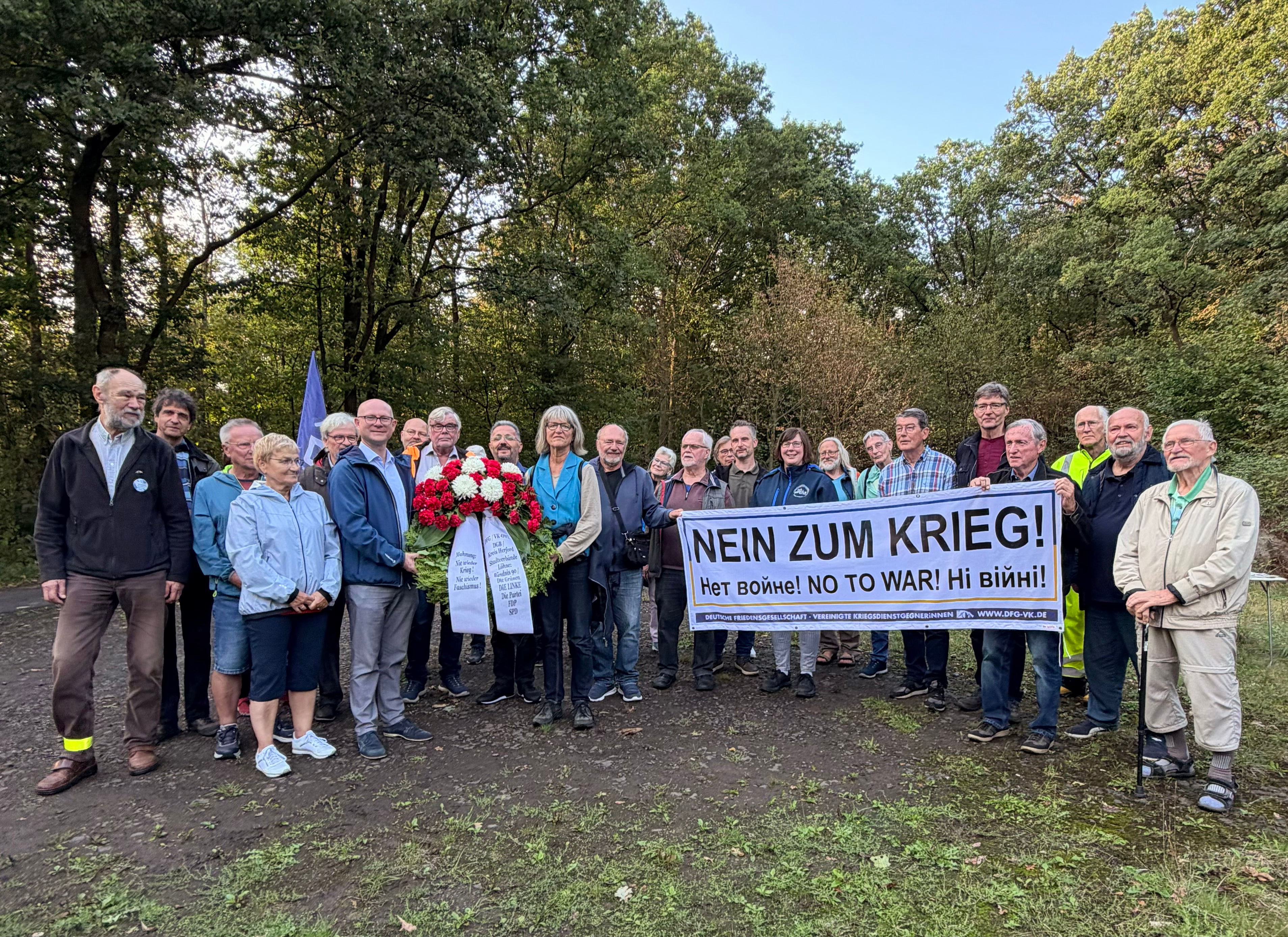Hauptteil der Teilnehmer präsentieren Kranz und Plakat "Nein zum Krieg!"